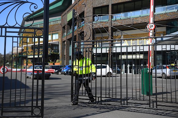 A security guard shuts the gates of The All England Tennis and Croquet Club on Wednesday.