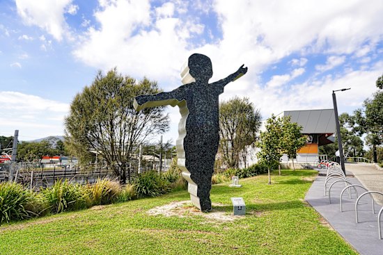 A sculpture at Bayswater train station of a little boy doing an aeroplane stance.