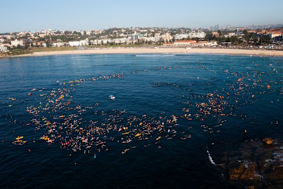 Large numbers of people join the paddle-out at Bondi Beach.