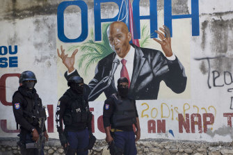 Police stand near a mural featuring Haitian President Jovenel Moise, near the leader’s residence where he was killed by gunmen.