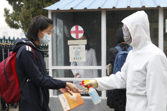 A schoolgirl wearing face mask, disinfects her hands before entering the Kumsong Secondary School No. 2 in the morning in Pyongyang, North Korea.