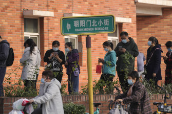 Masked residents line up to receive booster shots against COVID-19 at a vaccination site in Beijing on Monday.