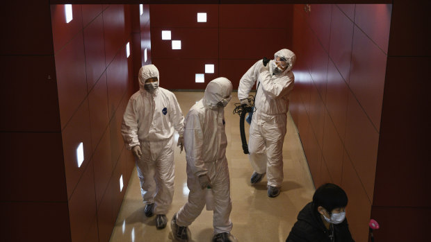Workers wear protective suits in a mall in Beijing, China. 