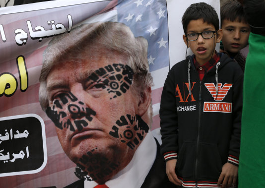 A boys next to a desecrated poster of US President Donald Trump during a rally in Islamabad, Pakistan on Sunday.