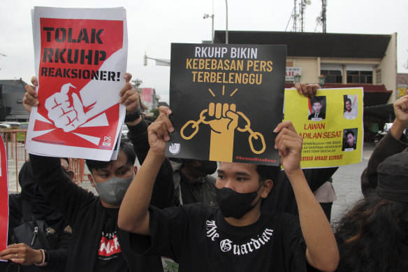 Activists hold up posters during a rally against Indonesia’s new criminal law.