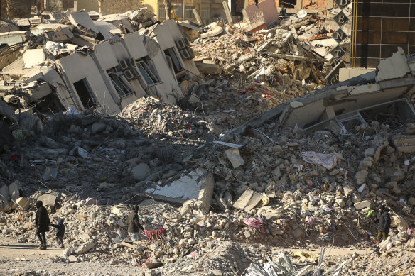 People stand by a collapsed building in Adiyaman, southern Turkey, on February 13.