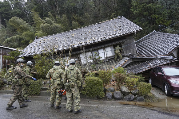 Japanese Self Defence Force members inspect a collapsed house hit by earthquakes in Suzu, Ishikawa.