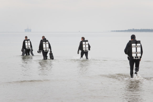 Divers enter the water on the third day of a search for a missing snorkeller. 