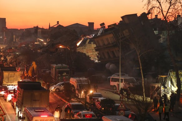 People walk among collapsed buildings, in Adiyaman. Emergency crews made a series of dramatic rescues in Turkey on Friday, pulling several people, some almost unscathed, from the rubble.