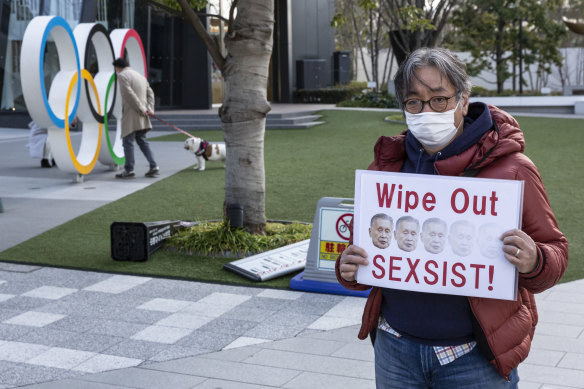 A man holds a placard with pictures of Tokyo Games boss Yoshiro Mori during a protest in Tokyo.