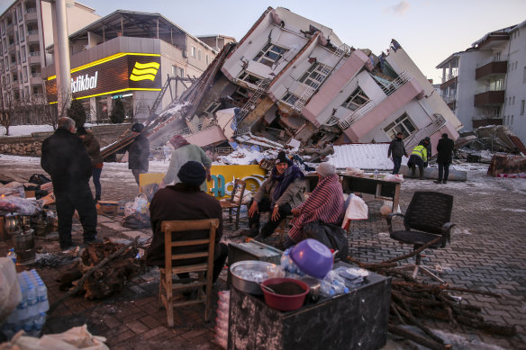 People stand by collapsed buildings in Golbasi, in Adiyaman province, southern Turkey.