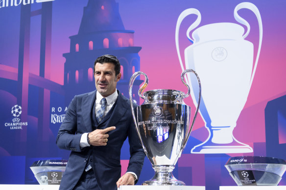 Luis Figo poses with the Champions League trophy at the draw for the round of 16.