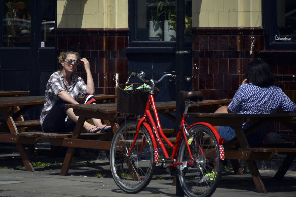 Two women sit outside a closed pub in London as Britain faces its seventh week of coronavirus lockdown.