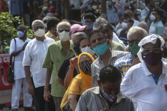 People queue in Mumbai, India, on Monday to receive their COVID-19 vaccine.