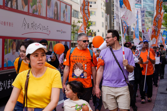 Fransız baba Phillipe Cocatrix (ortada), Mayıs ayında anne babaları tarafından kaçırılan diğer kurbanlarla birlikte Tokyo'da yürüyor. 