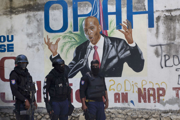 Police stand near a mural featuring Haitian President Jovenel Moise, near the leader’s residence where he was killed by gunmen.