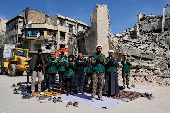A cleric leads a group of volunteers in prayer next to a police facility struck during the U.S.Israeli military campaign in Tehran, Iran, Wednesday, March 4, 2026. (AP Photo/Vahid Salemi)