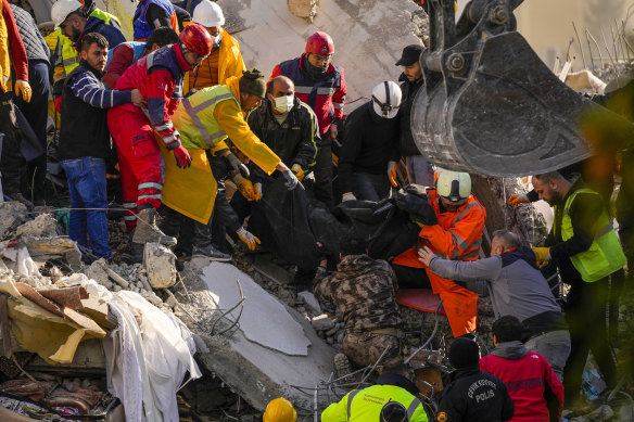 Emergency workers carry a body found in the rubble of a destroyed building in Adana, Turkey.