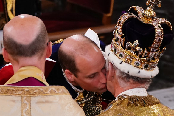 Prince William kisses his father, King Charles III, during the coronation ceremony.