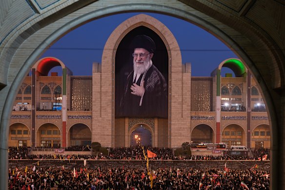 Mourners gather beneath a portrait of the late Iranian Supreme Leader Ayatollah Ali Khamenei during the funeral ceremonies for Khamenei and members of his family.