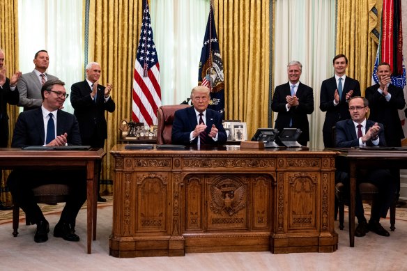 US President Donald Trump, centre, Serbia President Aleksandar Vucic, left, and Kosovo's PM Avdullah Hoti applaud following the signing ceremony in the Oval Office.