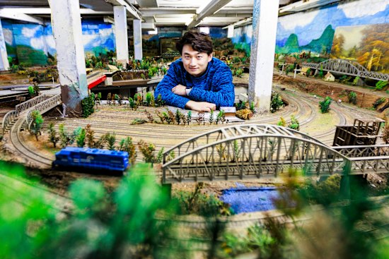 Daniel Xu in the crawl space under the house he bought where he discovered a full train set.