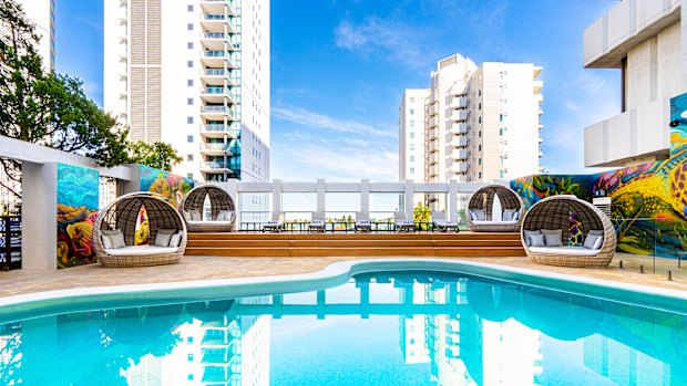 The open-air pool terrace is surrounded by vibrant murals.