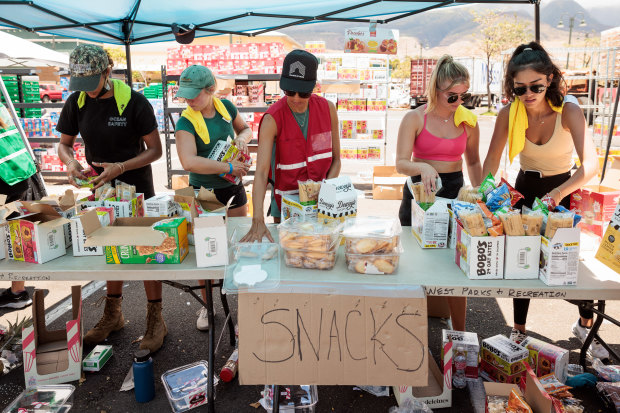 Volunteers sort through donated food items at an emergency aid distribution point for victims of last week’s wildfire in Lahaina, on the Hawaiian island of Maui.