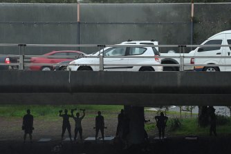 Sheltering from showers of rain, people exercise under traffic on Sydney’s City West Link on Friday morning.