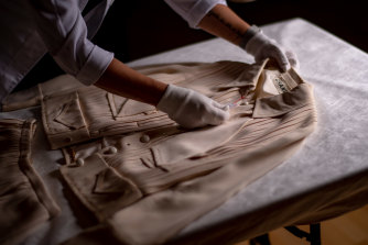 A beige jacket and skirt (Spring 1971) being prepared by textile specialist Vicki Car at the NGV.