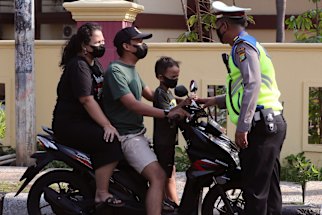 A police officer stops motorists at a check point in Jakarta.