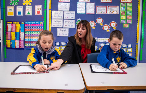 Assistant principal Michelle Looker reads with students Savannah Brock, 6, and Jasper Douglas, 7.