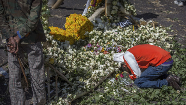 An Ethiopian relative of a crash victim mourns and grieves next to a floral tribute at the scene where the Ethiopian Airlines Boeing 737 Max 8 crashed shortly after takeoff on March 15.