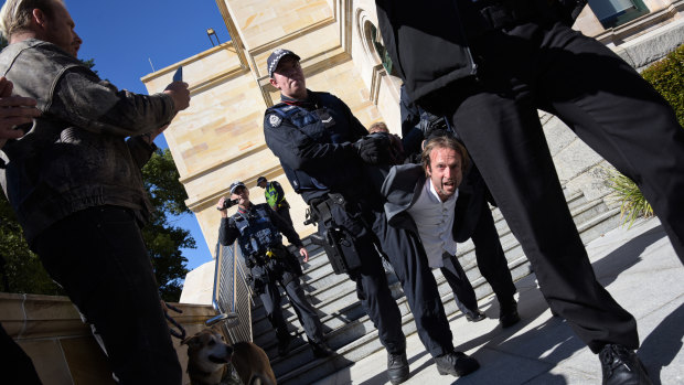 A man arrested by WA police is carried down the steps at Parliament House.