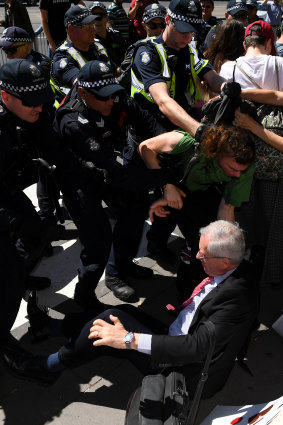 Police intervene to protect Shaun Islip, lying on the ground, from protesters outside the Melbourne Exhibition and Convention Centre during the climate protests on October 29.