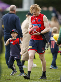 Oliver signs a footy at training.