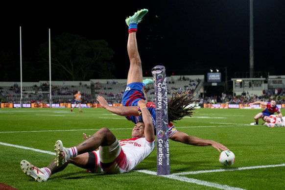 Newcastle winger Dominic Young flips over the try line to score against the Dragons.