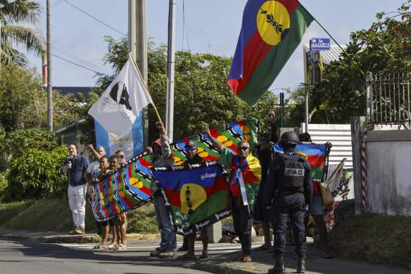 People demonstrate as French President Emmanuel Macron’s motorcade drives past in Noumea, New Caledonia.