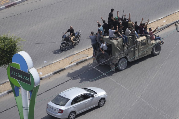 Hamas militants drive a captured Israeli military vehicle in Gaza City on October 7.