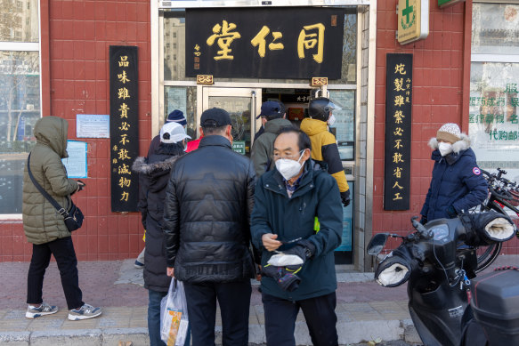 Residents in Beijing wait to go into a pharmacy as China loosens its restrictions across the country. 