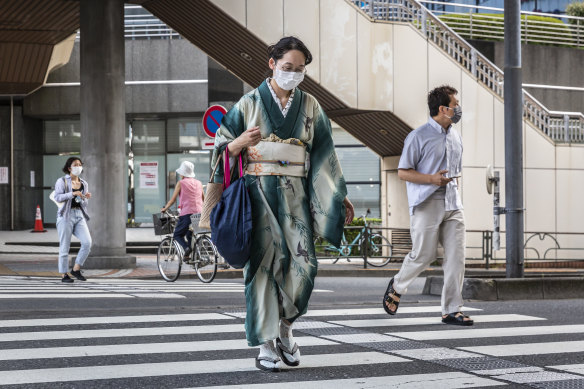 A woman in Kimono wearing a face mask crosses a street on July 29, 2021 in Tokyo. Fans have been barred from most Olympic events due to the COVID-19 pandemic. 