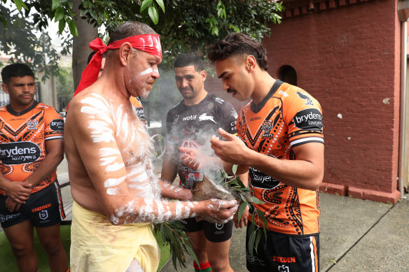 Daine Laurie, Tyrone Peachey and Cody Walker take part in a smoking ceremony for Indigenous Round on Tuesday.