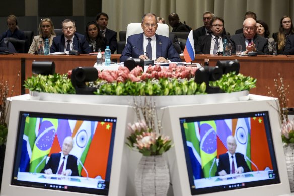 Russia’s Foreign Minister Sergei Lavrov (centre) looks on as Russian President Vladimir Putin delivers his BRICS summit remarks via video link.