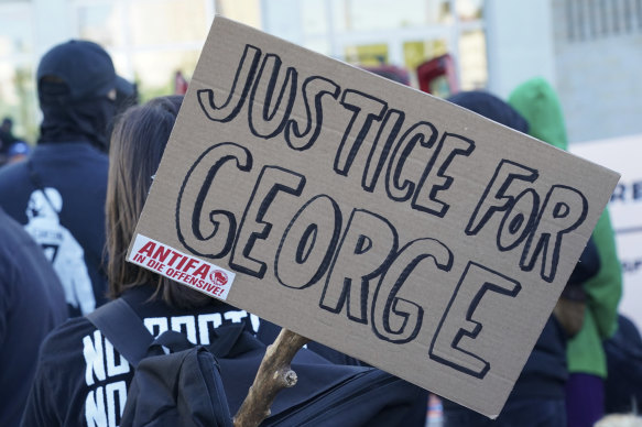 A poster with the inscription 'Justice for George' and 'Antifa on the offensive' is held by a protester demonstrating against police brutality.