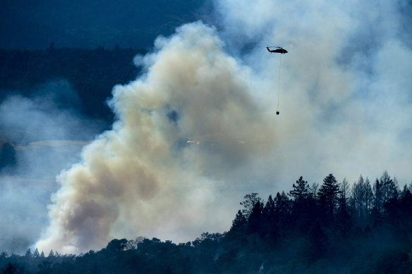 A helicopter passes a smoke plume as the Kincade Fire burns in unincorporated Sonoma County, California.