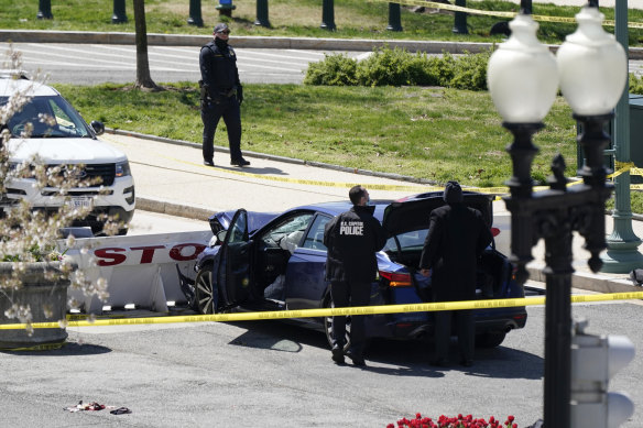 Police stand near a car that crashed into a barrier near the US Capitol.