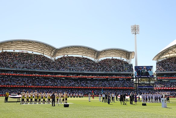 Australian and English cricketers listen to a performance by John Williamson as a tribute to the Bondi shooting victims.