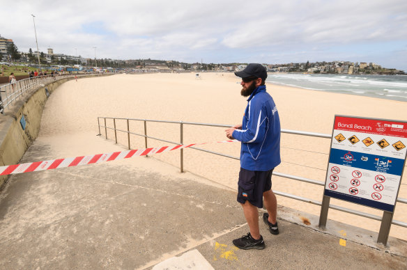 A ranger tapes off an entrance to Bondi Beach on Saturday afternoon. 