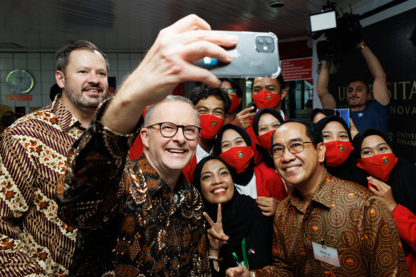 Industry and Science Minister Ed Husic and Prime Minister Anthony Albanese take a selfie with students at the Universitas Hasanuddin in Makassar, Indonesia.