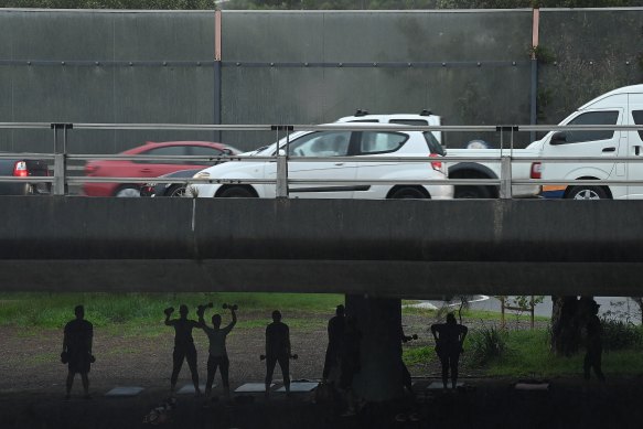Sheltering from showers of rain, people exercise under traffic on Sydney’s City West Link on Friday morning.